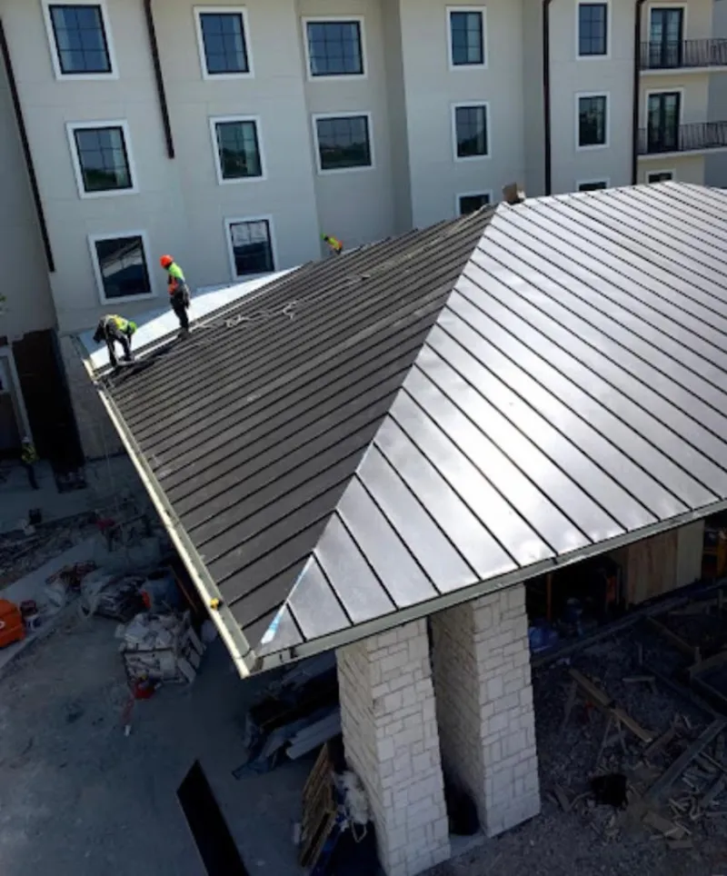 Crew installing standing seam metal roof panels on a commercial project in Wheatfield